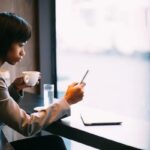 woman drinking coffee and looking at phone