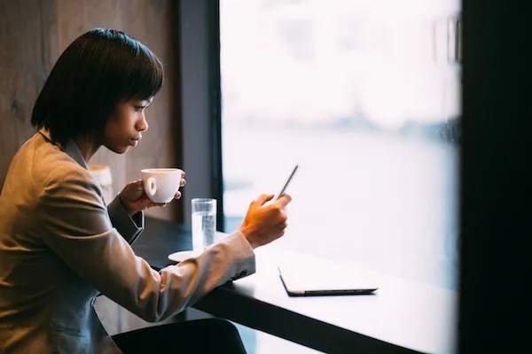 woman drinking coffee and looking at phone