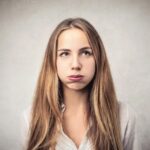Woman with cheeks puffed out looking up