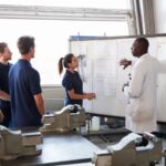 presenting at a whiteboard; man and woman teaching group at a whiteboard