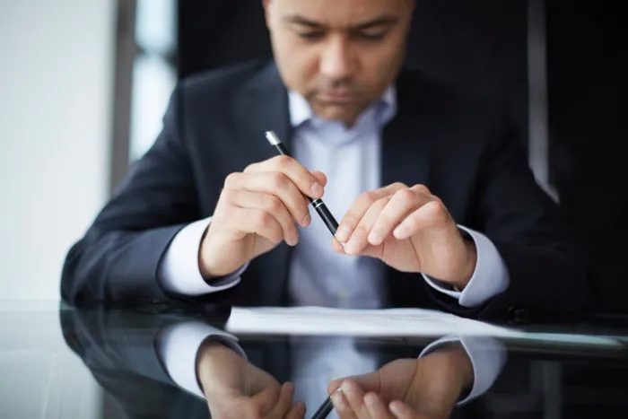man reading a paper with a pen in his hand; business man; professional man