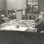 old fashion image; man speaking at a table; man presenting at table