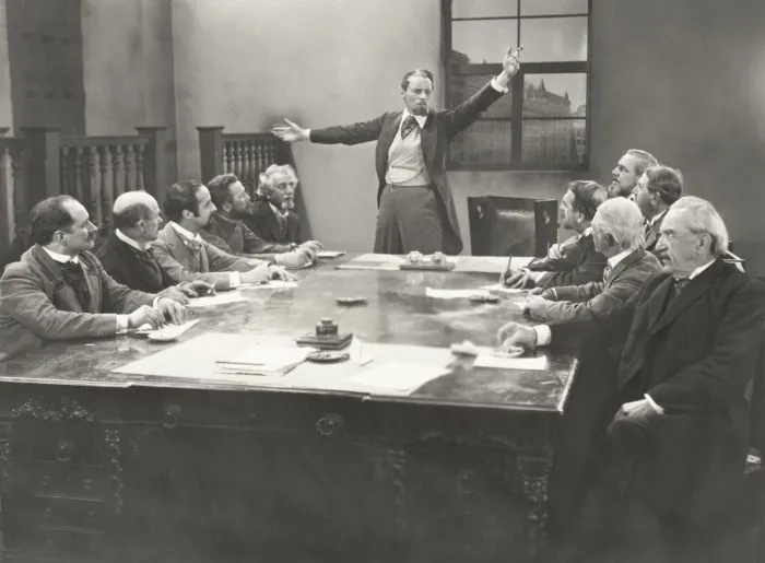 old fashion image; man speaking at a table; man presenting at table