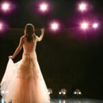 Woman in a dress on stage; woman singing on stage