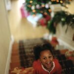 child on stairs smiling with holiday decorations in the background