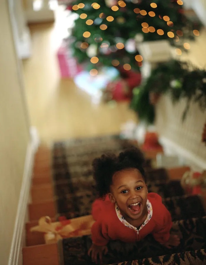 child on stairs smiling with holiday decorations in the background